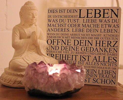 Komposition Schild mit Spruch, Kerze und weisser Buddha